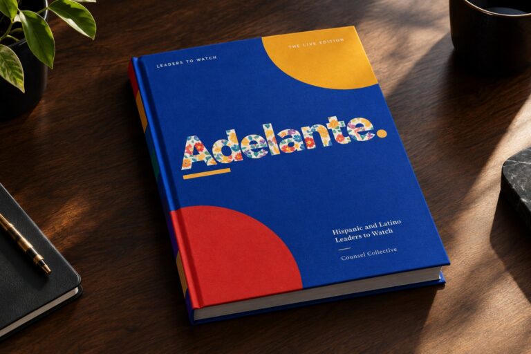 The Adelante hardcover, cobalt with marigold and red circles and a floral wordmark, on a wooden desk